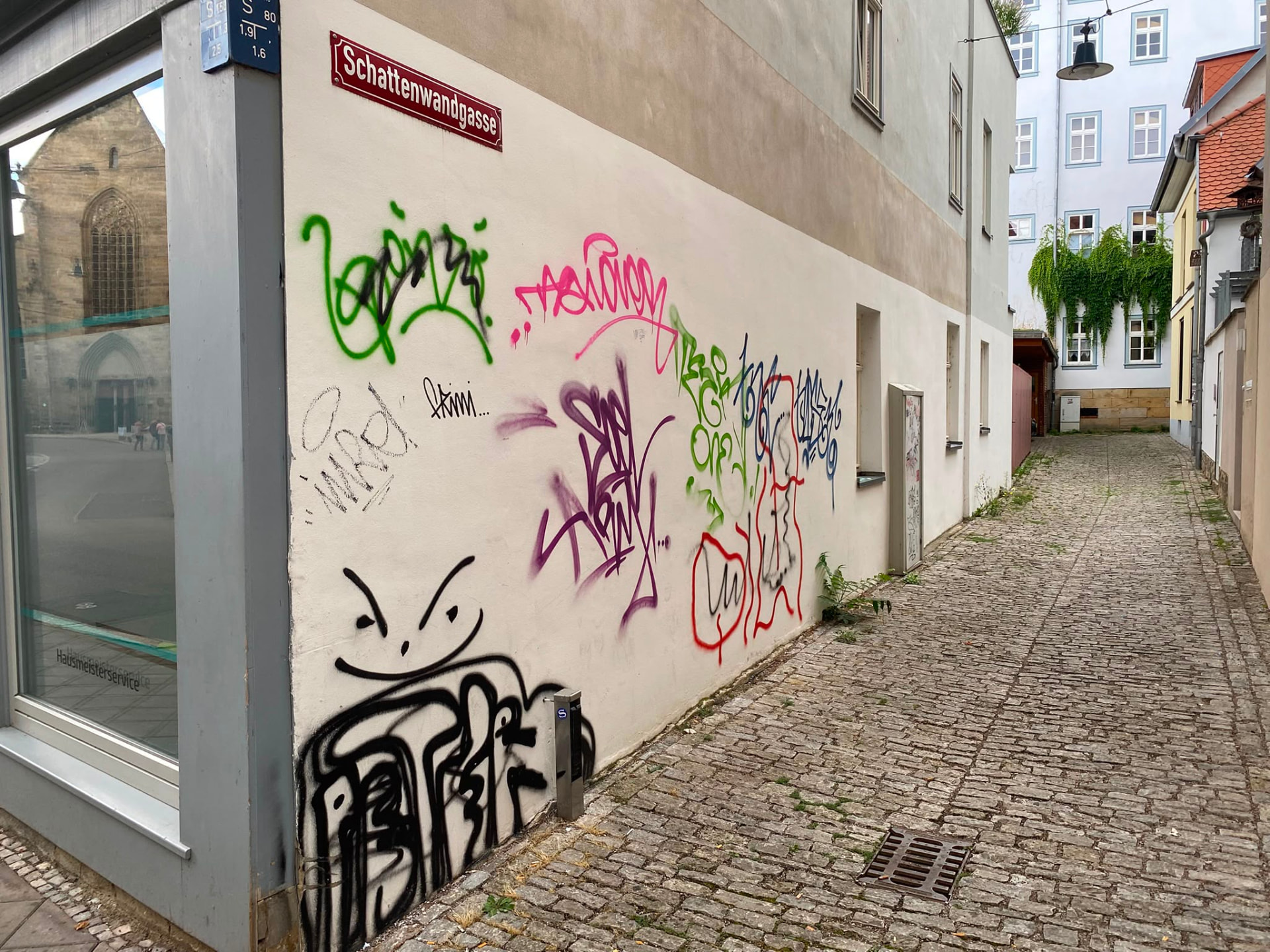 Mit Tags und Schriftzügen besprühte Hauswand in einer Altstadtgasse